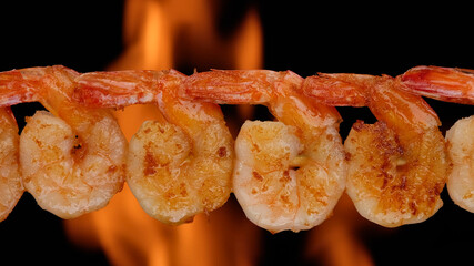 fry shrimps on open fire. Grilled shrimps with Flame fire on background.