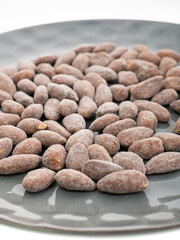 almonds with sweet sprinkles on a plate on a white background
