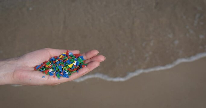 Microplastic water pollution. A woman hold microplastic in her hand and protect ocean from pollution.