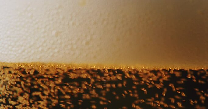 Extreme close up of beer foam filling up a clean glass. Filmed in 4k DCI super slow motion.