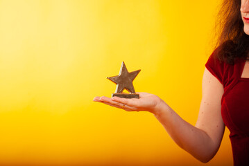 a woman holds a statuette in the form of a star in her hand on a boat in isolation on a yellow...
