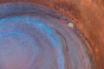 The inner of a copper cauldron with blue circles. Oxidation. Soldering on a copper surface. Repair of copper pots. Copy space. 