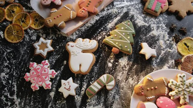 Christmas decorated cookies collection. Festive bakery food. Homemade gingerbread pastry. Unrecognizable female taking bite star figure icing biscuit floured black desk background.