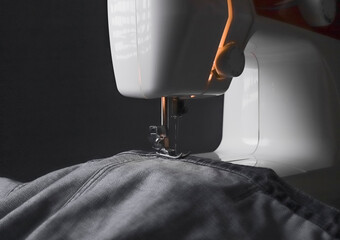 Denim cloth on sewing machine closeup. Small business concept.
