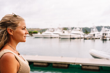 Fototapeta na wymiar Blonde woman in a pier looking at moored yachts
