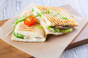 fried sandwich with meat mushrooms vegetables on paper and wooden board