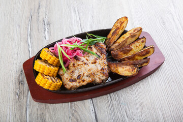 fried pork with fried potatoes and corn in a pan
