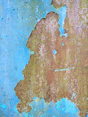 background of a very old metal rusty wall painted with bright blue paint that has begun to flake off