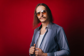 A man with long hair in a plaid shirt and white T-shirt, in blue jeans. The guy with the mustache...