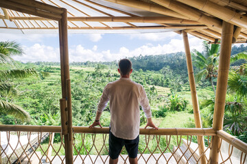 A successful man in a villa admiring the view of the rice fields.