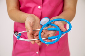 Stethoscope in hands of female doctor in pink medical uniform. Life and health insurance. Professional examinations. Medicine and health. A healthy lifestyle. Modern medicine.