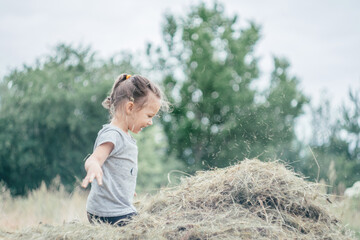 Little girl 3-4 years old jumps and plays in hay stack, throwing it up. Motion blur © Евгения Рубцова