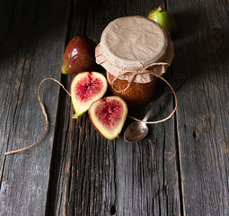 Fig jam in a glass jar with fresh figs on an old wooden table.  Space for text. Top view.