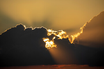 The sunset rays of the sun make their way through the clouds. The golden sky at sunset is a beautiful color of the sky.