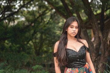 A voluptuous young Filipina woman posing at the park. A serious yet alluring look.