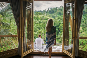 A couple in love sits in a villa in Bali and admires the view of the rice fields.