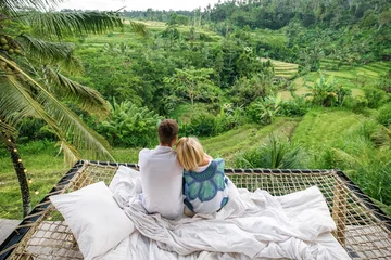 Stoff pro Meter A couple in love sits in a villa in Bali and admires the view of the rice fields. © Evgenii