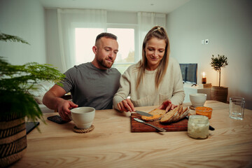 Caucasian couple eating breakfast in kitchen buttering toast