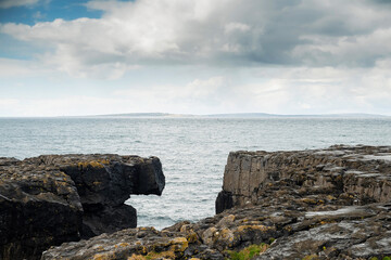 Fototapeta na wymiar Rough stone coast line. West coast of Ireland. Burren area. Dark storm clouds over ocean surface. Nobody. Irish landscape