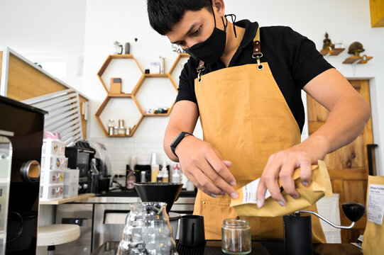 Barista hands pouring fresh roasted coffee beans for weighing on digital scale. Tools and equipment for making Drip Brew coffee