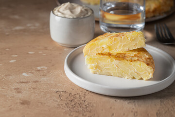 Tortilla Espanola, Spanish omelette made with eggs and potatoes  on white plate  served with traditional mayonnaise .