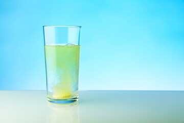dissolving tablet dissolves in water on blue background, studio shot. the medicine pill dissolves in a glass of water