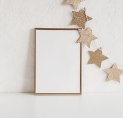Gold frame mockup blank paper and Christmas decoration stars garland with copy space. Christmas background. New Year Photo frame template.