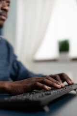 Closeup of african american hands typing management strategy on keyboard working at business presentation using university platform during lockdown in living room. Computer user at home