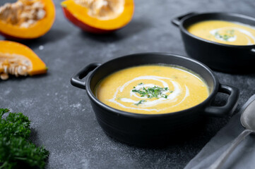 Squash vegan soup, creammy autumn soup in black bowl on dark background. Autumn foods.
