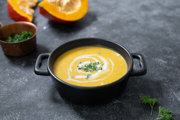 Bowl with pumpkin soup. Vegan creamy soup with coconut milk and butternut squash. Top view. Dark background.