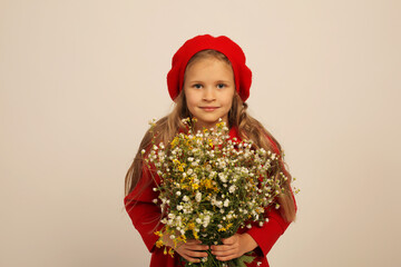 a beautiful girl in a red coat and a red beret holds wildflowers in her hands