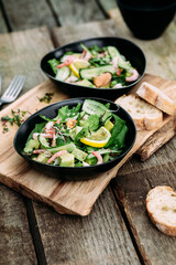 Salad with seafood, vegetables and herbs in a plate on a wooden table. Rustic style