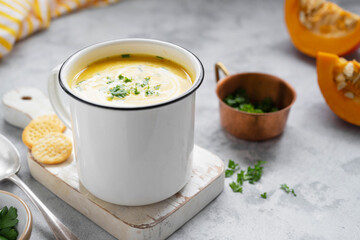 Squash or pumpkin vegan soup in metal mug with pumpkin slices.