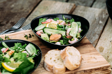 Salad with seafood, vegetables and herbs in a plate on a wooden table. Rustic style