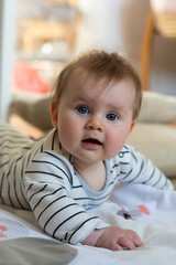 Baby girl child playing at home laying down on the floor. Baby development. Parenting and education.