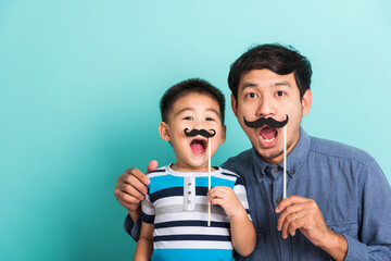 Family funny happy hipster father and his son kid holding black mustache props for the photo booth...