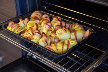 Potatoes and sausages on a baking sheet.
