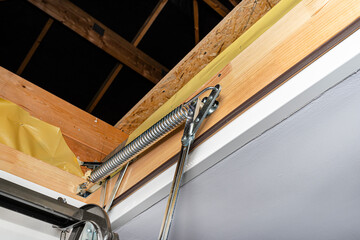 A spring tensioning mechanism that helps in opening a metal ladder to the attic placed in the...