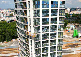 Suspended cradle for works of the facade of skyscraper. Construction of multi-storey building. Mobile scaffolding platform for construction work at height and plastering and wall painting.