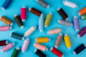 Colorful sewing thread in the studio on a blue color background