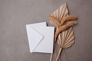 Bohemian blank invitation card surrounded by natural dried palm leaf and grasses. Wedding and celebration background