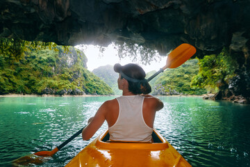 Woman paddling kayak inside from cave in Ha Long bay. Vietnam
