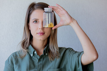 Fototapeta premium woman keeps transparent jar with pills at eye level