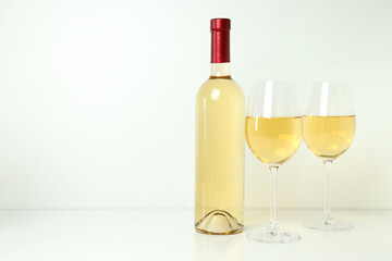 Bottle and glasses of wine on white table