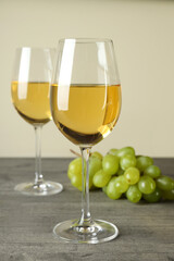 Glasses of white wine and grape on gray textured table