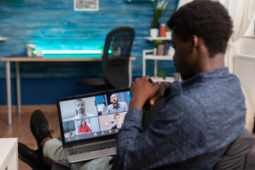 Student discussing marketing idea with college team during online videocall teleconference meeting using e-learning university platform. Conference telework on laptop in living room. Computer user