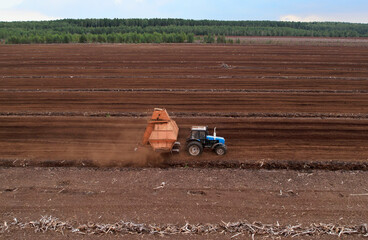 Obraz premium Peat Harvester Tractor on Collecting Extracting Peat. Mining and harvesting peatland. Area drained of the mire are used for peat extraction. Drainage and destruction of peat bogs.