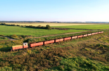 Train transports peat in freight wagons from peat extraction. Aerial view of the diesel locomotive...