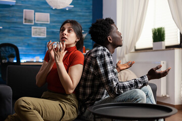 Interracial couple screaming while sitting on sofa. Angry mixed race people fighting about marriage...