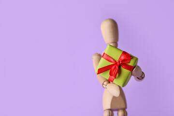 Wooden mannequin with gift box on color background
